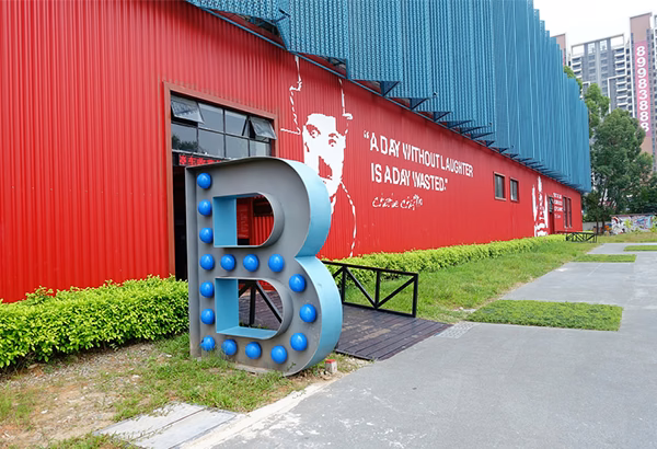 Rote Gebaeudefassade mit grossem Buchstabenobjekt und Gehweg davor